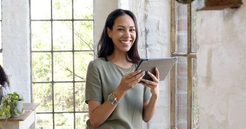 Professional Female Using Tablet By Sunlit Window, Embracing Technology and Nature