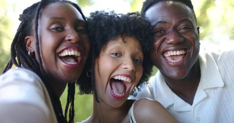 Joyful african american friends laughing together in sunlit park close-up candid portrait