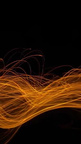 Vertical video showing golden light ribbons flowing and dancing across black canvas