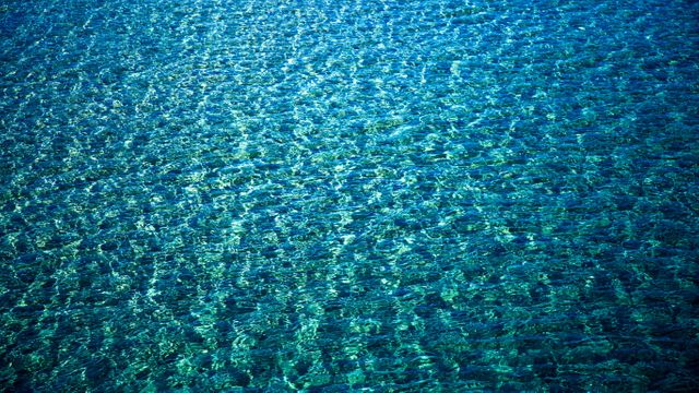 The image captures the tranquil surface of blue ocean water, creating a serene and refreshing feel. The ripples and turquoise hues enhance its calming effect. Ideal for backgrounds, nature projects, aquatic-themed advertising, and spa or wellness promotions.