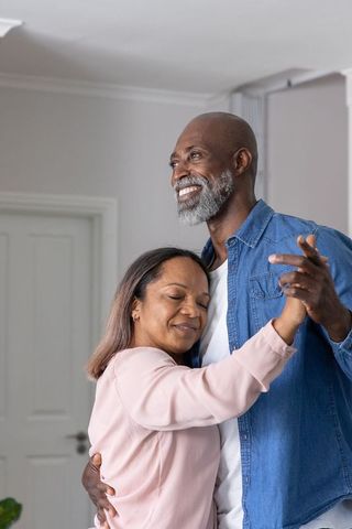 Mature black couple slow-dancing embracing cozy home interior warm lifestyle moment
