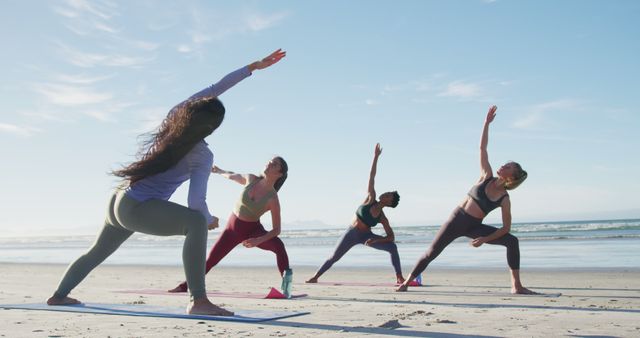 Group of diverse women practicing yoga on the beach during sunrise, providing a peaceful and relaxing atmosphere ideal for ads or articles on wellness, outdoor activities, fitness classes, healthy living, and mindfulness.