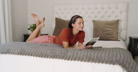 Woman relaxing on bed reading book in cozy bedroom