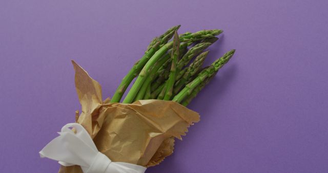 Image of fresh asparagus wrapped with white ribbon and copy space over lilac background. fusion food, fresh vegetables and healthy eating concept.
