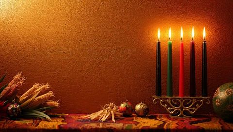 Kinara candles burning on colorful textile mantel with corn and ornaments for kwanzaa