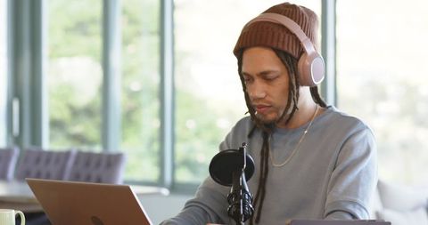 African american creator recording podcast at home studio with laptop and microphone