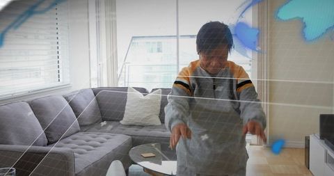 Senior chinese woman touching hologram augmented reality interface in modern living room