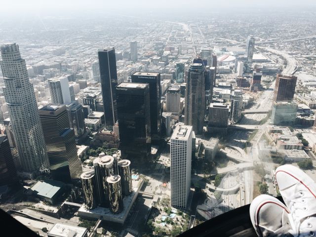 Aerial shot featuring downtown Los Angeles showcasing prominent skyscrapers. The expansive cityscape stretches out under a clear, sunny sky. Ideal for illustrating urbanization, city planning, business, and travel articles or presentations. Suitable for blogs, business websites, travel brochures, educational materials on metropolitan growth and infrastructure.