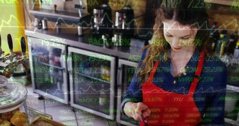 Businesswoman manages transactions amidst financial data overlay