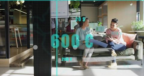 Two colleagues collaborating on tablet in modern coworking lounge with teal data overlay