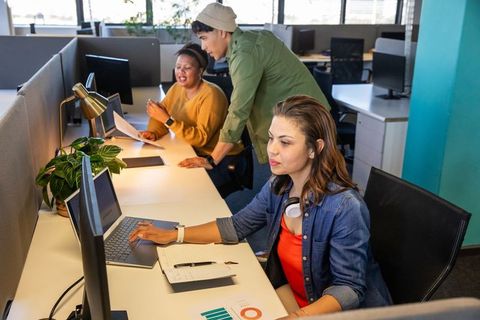 Young professionals collaborating in modern open-plan office with laptop and headset