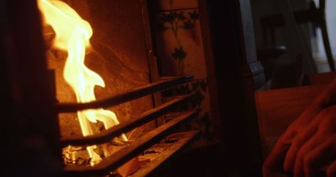 Person adding firewood to cozy fireplace indoors