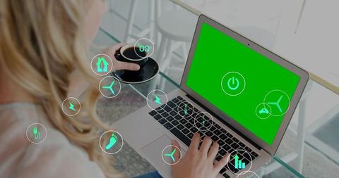 Woman typing on laptop holding coffee with green power interface and sustainability icons