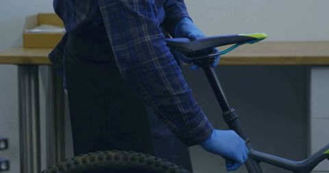 Mechanic Adjusting Mountain Bike Saddle in Workshop
