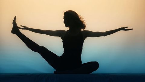 Balancing yoga silhouette holding extended leg and arms in graceful stretch