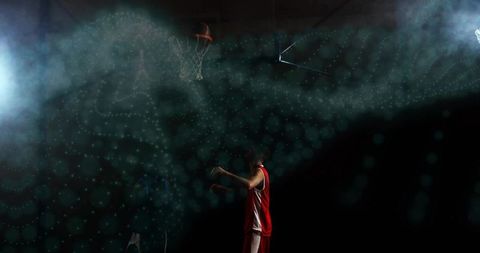 Finishing spotlit basketball shot under rim in hazy arena with dramatic dust and hoop