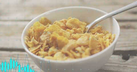 Crunching Cornflakes in White Bowl with Spoon on Rustic Wooden Table with Teal Data Overlay