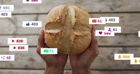 Male hands holding artisan round loaf with social media notifications and rustic wood background