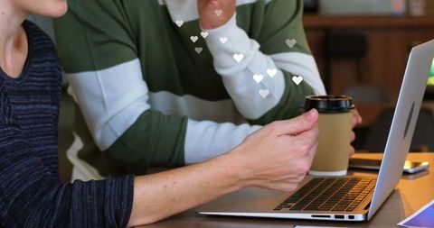 Business professionals collaborating on laptop with heart graphics