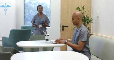 African american healthcare staff working in modern clinic breakroom with laptop and coffee