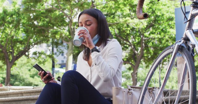 Woman Sitting Outdoors Drinking Coffee and Using Smartphone in Park - Download Free Stock Images Pikwizard.com