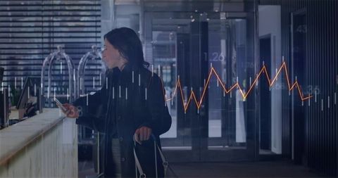 Business traveler checking phone at hotel lobby with financial data graph overlay