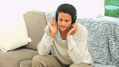 Man with Headphones Relaxing on Sofa Listening to Music