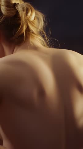 Vertical closeup video showing bare back and shoulder silhouette with soft studio lighting