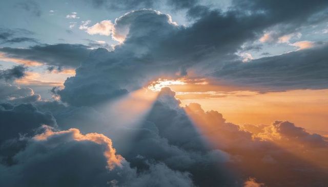 Sunlight piercing towering cumulus clouds at sunrise creating dramatic golden rays