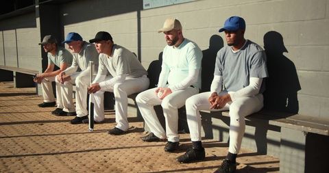 Sunlit baseball team sitting in dugout waiting between innings showing focus and camaraderie
