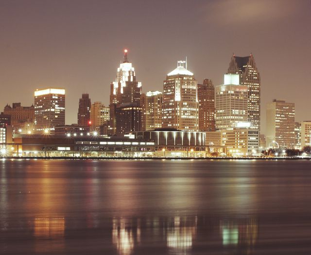 Detroit's illuminated urban skyline at night, beautifully reflected in the serene river water. Ideal for showcasing Detroit's vibrant night life, urban development, architecture, travel, tourism, and promotional materials for Michigan appeals.