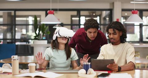 Classmates collaborating with virtual reality headset and tablet in modern study space