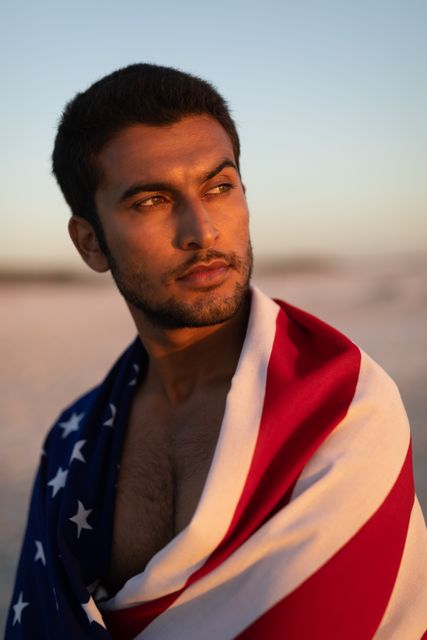 Man wrapped in American flag standing on the beach - Download Free Stock Photos Pikwizard.com