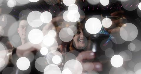 Friends toasting and capturing selfie in car cabin with bokeh lights and reflections