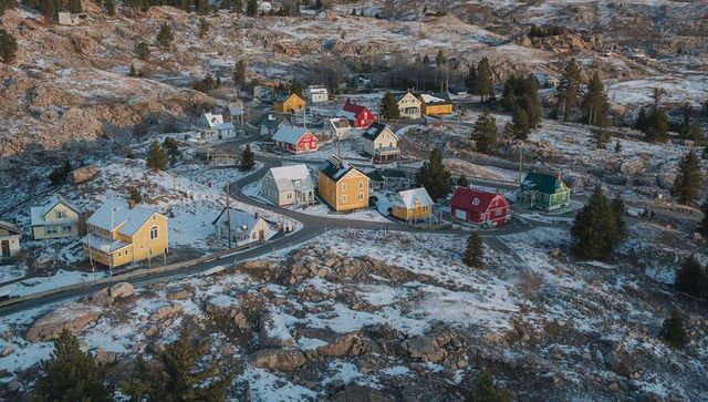 Colorful Coastal Cottages on Snow-Dusted Rocky Hillside with Winding Road