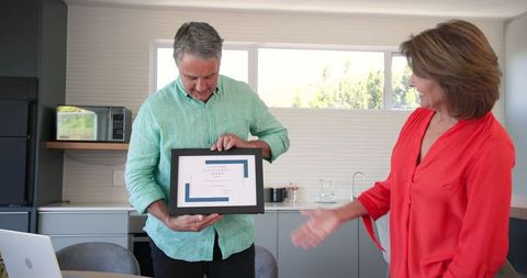 Senior couple viewing picture frame in contemporary kitchen