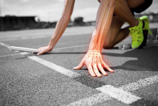 Image shows an athlete in starting position on running track, with digital overlay highlighting bones in hand. Suitable for use in sports health articles, rehabilitation programs, fitness blogs, and educational materials about human anatomy.