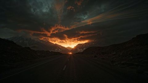 Lone Road Leading to Majestic Sunrise Over Mountain Peaks