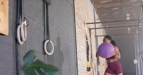 Athletic Woman Training with Medicine Ball in Gym for Endurance and Strength