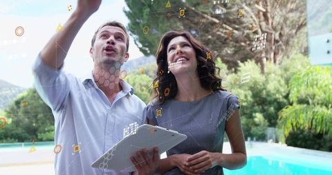 Business partners pointing and exploring augmented reality interface at backyard poolside