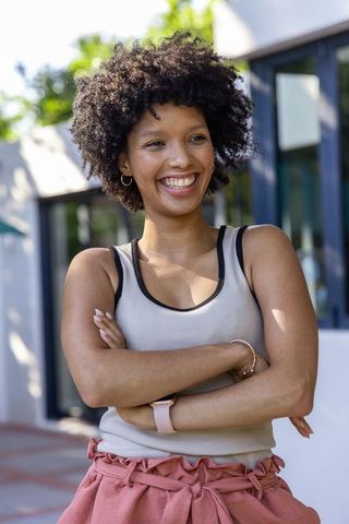 Smiling african american woman crossing arms wearing smartwatch and hoop earrings casual