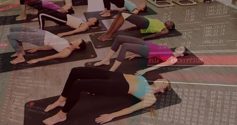 Women practicing bridge pose in group yoga class with digital encryption overlay