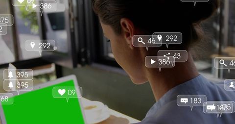 Woman working on laptop at cafe with social media notifications and green screen mockup