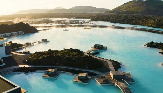 Relaxing in milky-blue geothermal lagoon with wooden boardwalks and morning mist