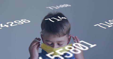 Boy lowering yellow face mask with floating numeric overlay, health data privacy concept