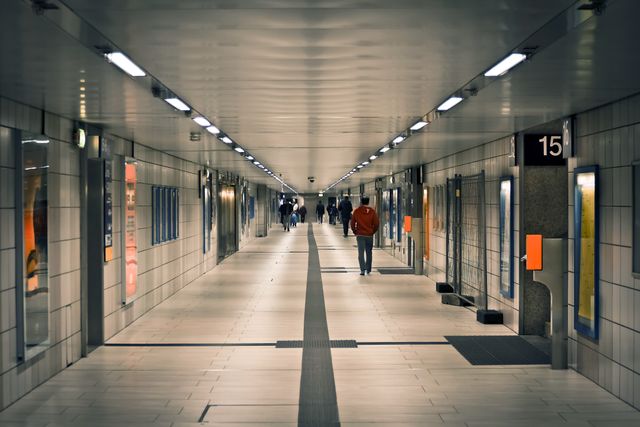 Contemporary tiled underground passageway with people walking to work or school. Ideal for content related to urban life, public transport efficiency, daily commute, and modern infrastructure.