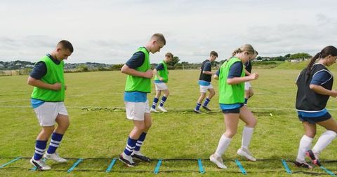 Soccer team performing agility drills on green field for training