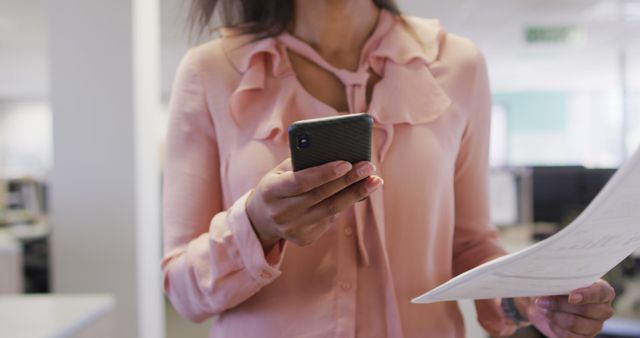 Businesswoman Checking Smartphone and Documents in Office - Download Free Stock Images Pikwizard.com