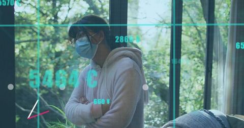 Masked teen standing by window wearing hoodie and glasses with teal data grid overlay