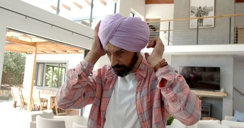 Man adjusting turban in sunlit modern living room